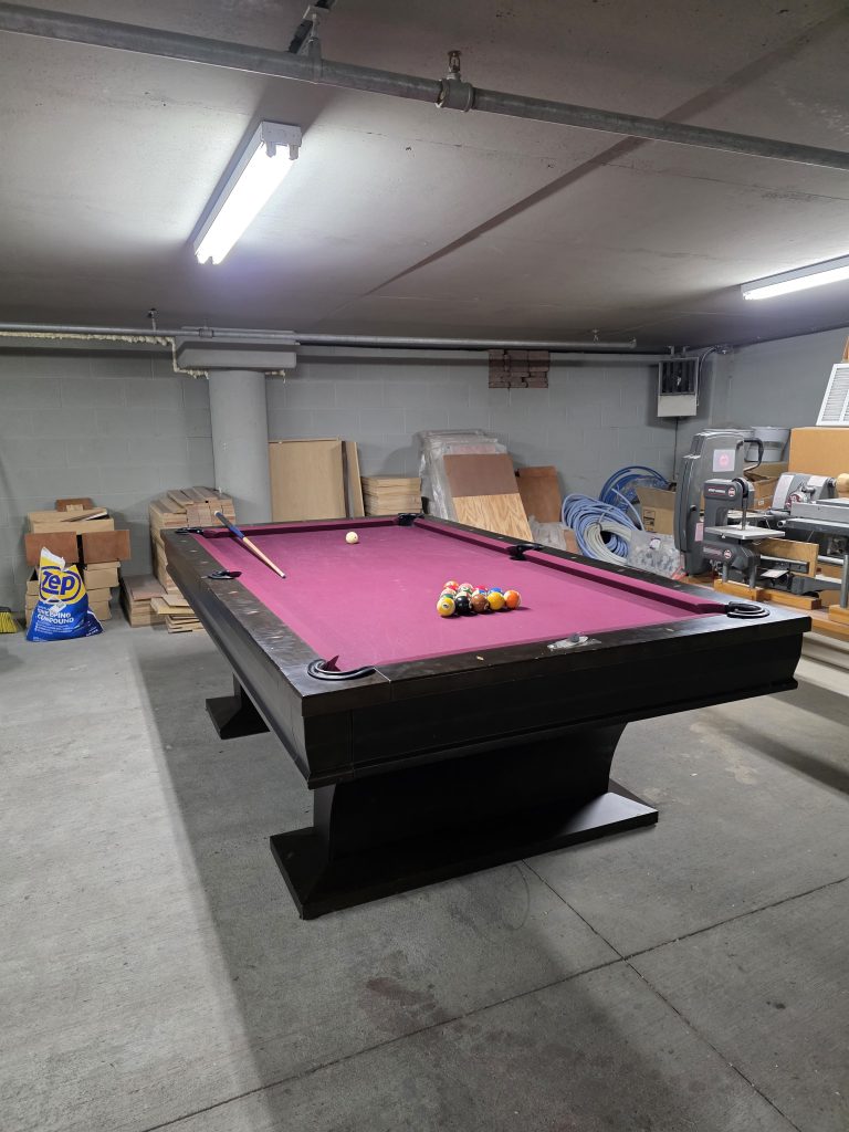 Experienced pool table movers in Aurora carefully disassembling and packing a billiard table
