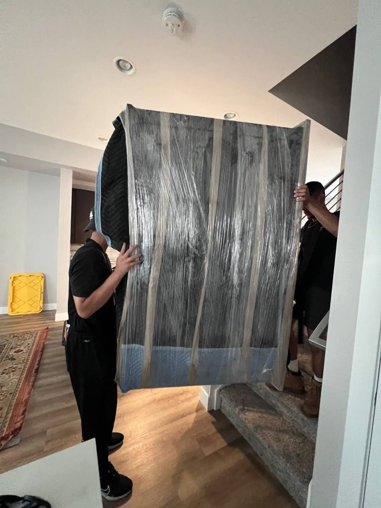 Professional same day movers from PackPalTeam carefully loading a sofa into a moving truck in Denver, Colorado.