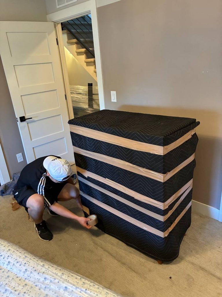 Professional piano moving team carrying upright piano up stairs in Denver home