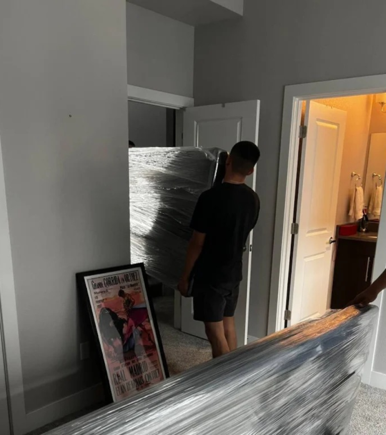 Upright piano being moved by insured professional piano movers in Denver, CO — safe handling with padded blankets and skid board